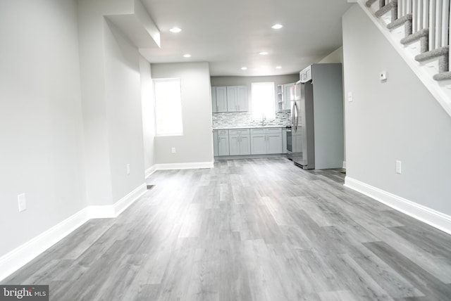 unfurnished living room featuring sink and light wood-type flooring