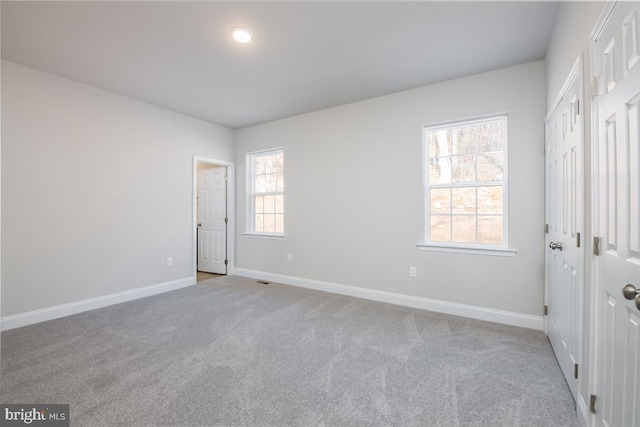 unfurnished bedroom featuring light colored carpet and multiple windows