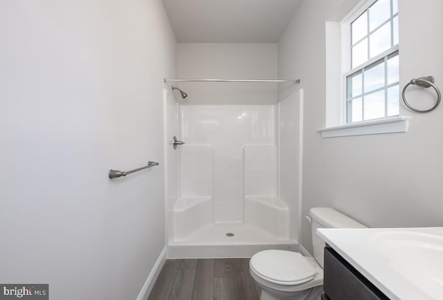 bathroom featuring vanity, wood-type flooring, a shower, and toilet