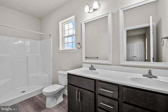 bathroom with a shower, hardwood / wood-style floors, vanity, and toilet