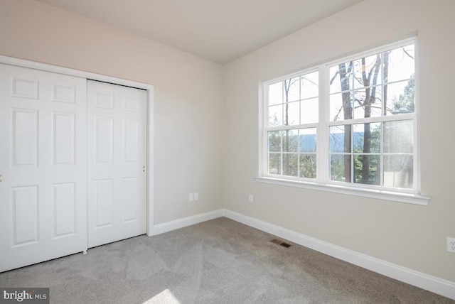 unfurnished bedroom with light colored carpet and a closet