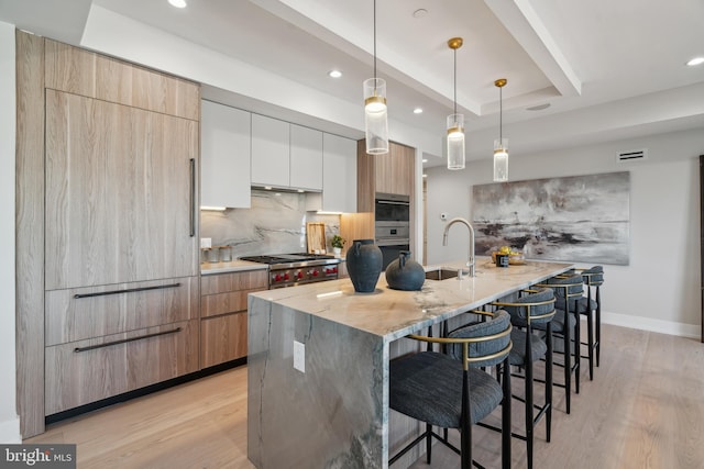 kitchen with hanging light fixtures, white cabinetry, a spacious island, and light hardwood / wood-style flooring