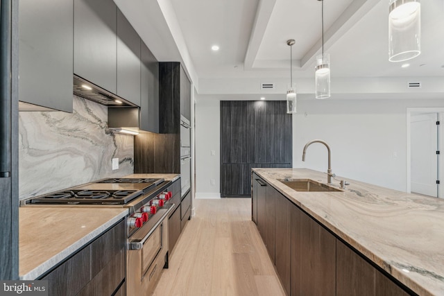 kitchen with range hood, sink, hanging light fixtures, stainless steel range, and light hardwood / wood-style flooring