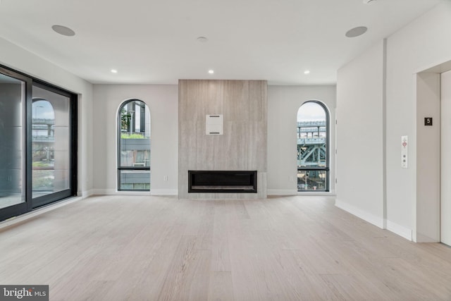 unfurnished living room with a large fireplace and light hardwood / wood-style flooring