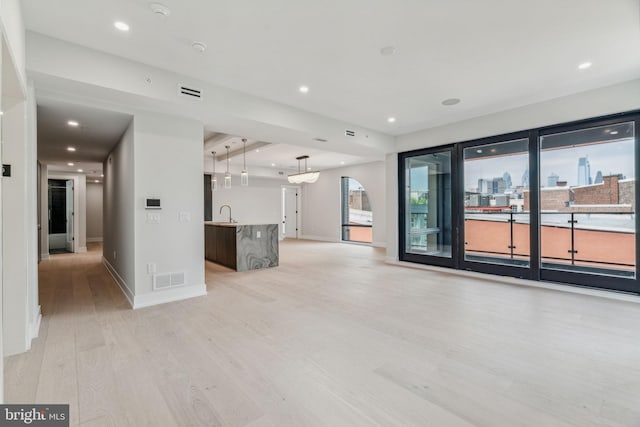 unfurnished living room featuring sink and light wood-type flooring