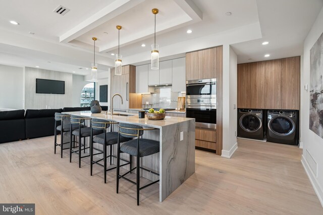 kitchen with white cabinets, separate washer and dryer, pendant lighting, and light wood-type flooring