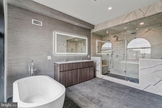 bathroom featuring independent shower and bath, vanity, and tile walls