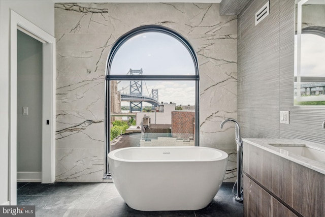 bathroom with a bathing tub, tile walls, and vanity