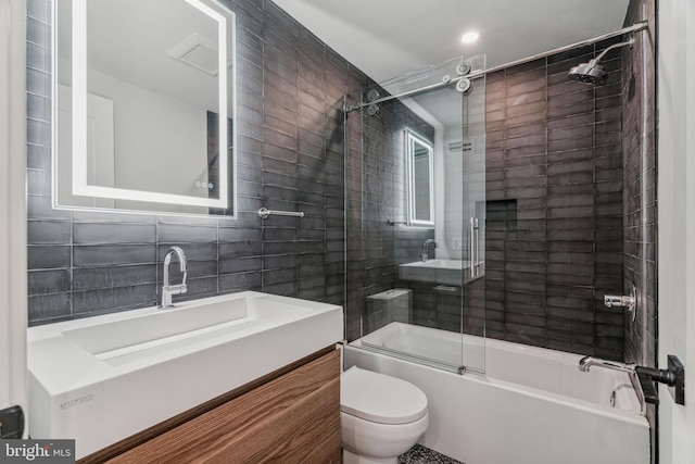 full bathroom featuring tile walls, vanity, bath / shower combo with glass door, and toilet