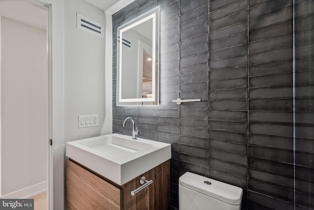 bathroom with vanity, tile walls, and toilet