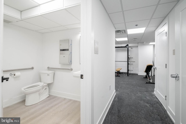 bathroom with hardwood / wood-style flooring, toilet, and a drop ceiling