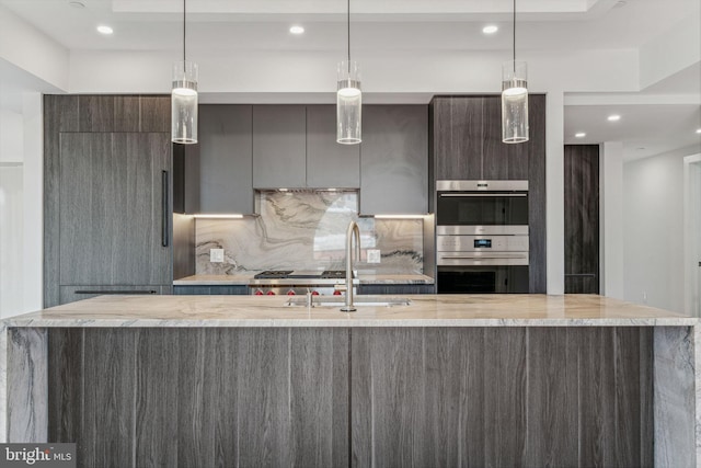 kitchen featuring pendant lighting, sink, and a kitchen island with sink