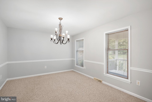 unfurnished room featuring carpet flooring and a notable chandelier