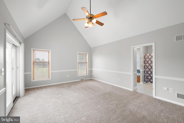 unfurnished bedroom with ceiling fan, light colored carpet, high vaulted ceiling, and ensuite bath