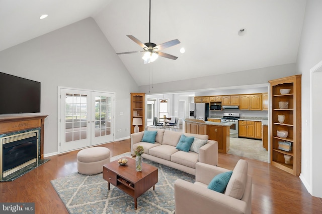 living room with light hardwood / wood-style flooring, high vaulted ceiling, french doors, and ceiling fan