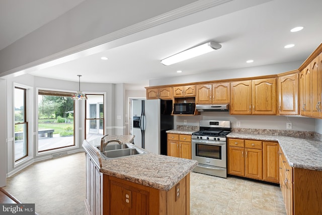 kitchen featuring pendant lighting, sink, stainless steel appliances, light stone counters, and a center island with sink