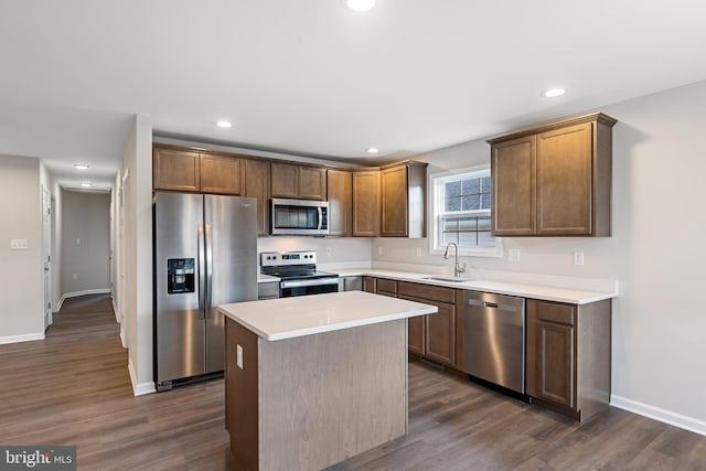 kitchen with appliances with stainless steel finishes, dark hardwood / wood-style flooring, and a kitchen island