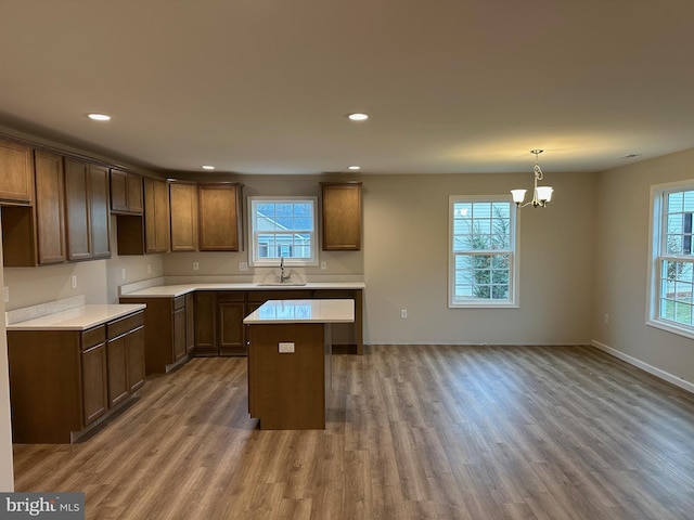 kitchen with hanging light fixtures, hardwood / wood-style flooring, a kitchen island, and sink