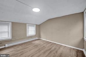 additional living space with lofted ceiling, hardwood / wood-style floors, and a baseboard radiator