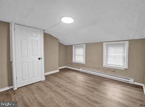 additional living space featuring a baseboard radiator and lofted ceiling