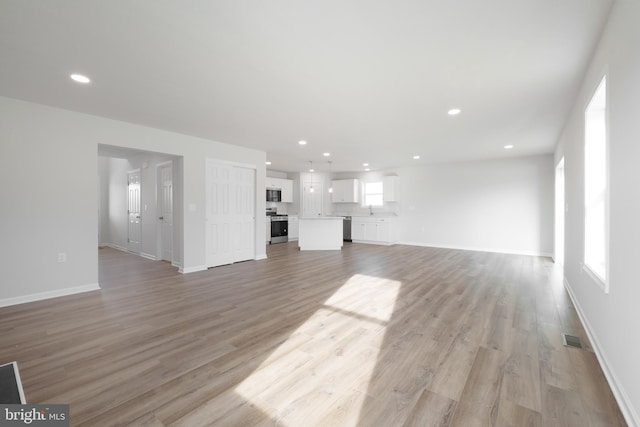 unfurnished living room with baseboards, visible vents, light wood-style flooring, and recessed lighting