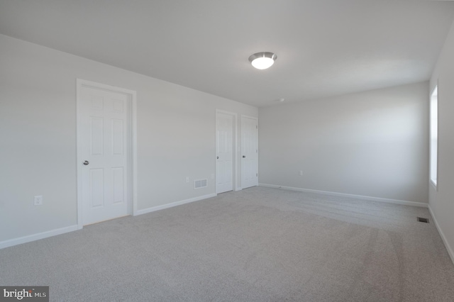 unfurnished room featuring light colored carpet, visible vents, and baseboards