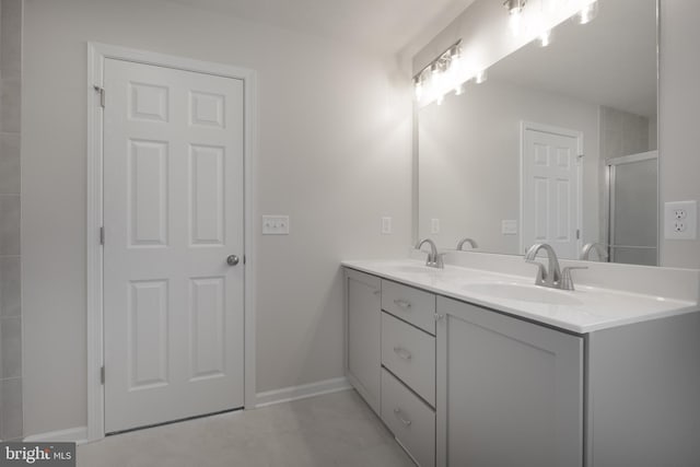 full bathroom featuring a shower with door, a sink, baseboards, and double vanity