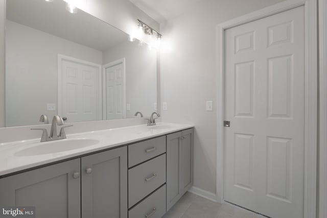 full bathroom featuring baseboards, double vanity, a sink, and tile patterned floors