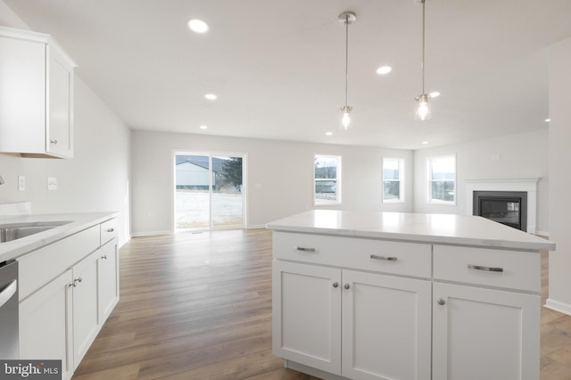 kitchen with light countertops, hanging light fixtures, open floor plan, white cabinetry, and a sink