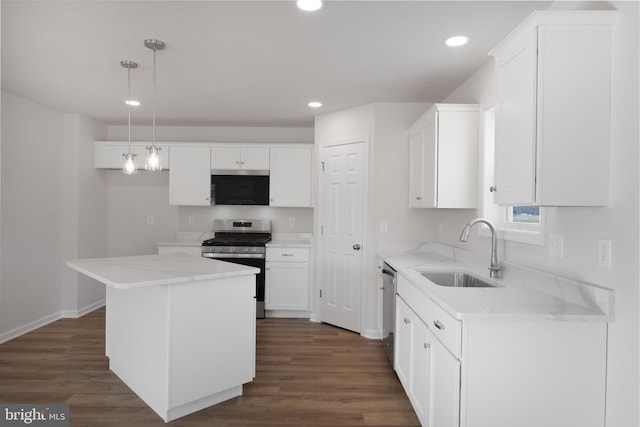 kitchen featuring white cabinets, appliances with stainless steel finishes, a center island, hanging light fixtures, and a sink