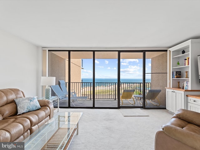 living room featuring light carpet, floor to ceiling windows, and a water view