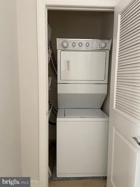 laundry area with stacked washing maching and dryer and tile patterned flooring