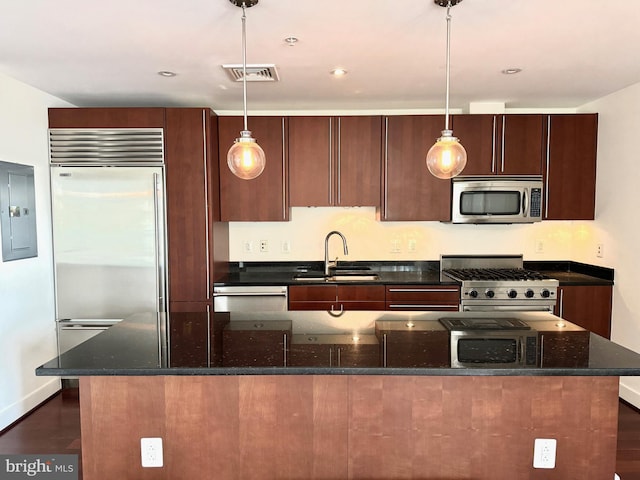 kitchen with sink, hanging light fixtures, high quality appliances, electric panel, and dark stone counters