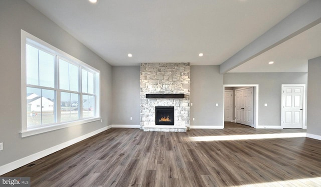 unfurnished living room with a stone fireplace and hardwood / wood-style floors