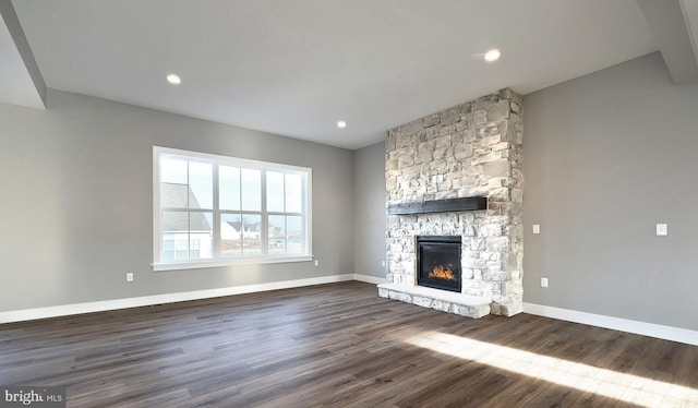 unfurnished living room featuring a stone fireplace and dark hardwood / wood-style flooring