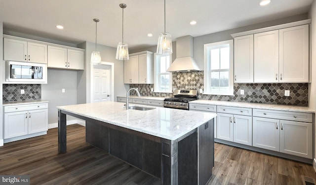 kitchen with built in microwave, sink, custom exhaust hood, stainless steel gas range oven, and white cabinetry