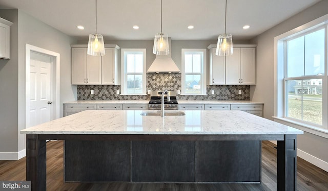 kitchen featuring sink, pendant lighting, light stone counters, and custom range hood