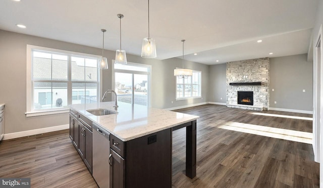 kitchen with dark wood-type flooring, stainless steel dishwasher, sink, and a center island with sink