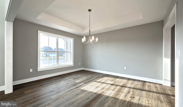 unfurnished dining area with hardwood / wood-style flooring, a raised ceiling, and a chandelier