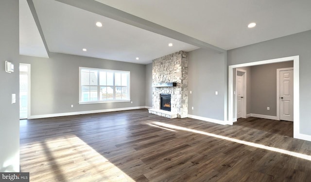 unfurnished living room with a stone fireplace and dark hardwood / wood-style floors