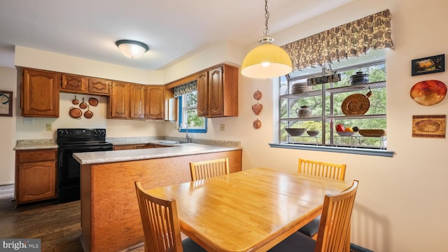 kitchen featuring sink, kitchen peninsula, decorative light fixtures, black electric range oven, and dark hardwood / wood-style floors