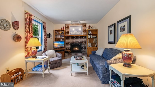 living room with carpet flooring, track lighting, a brick fireplace, and brick wall