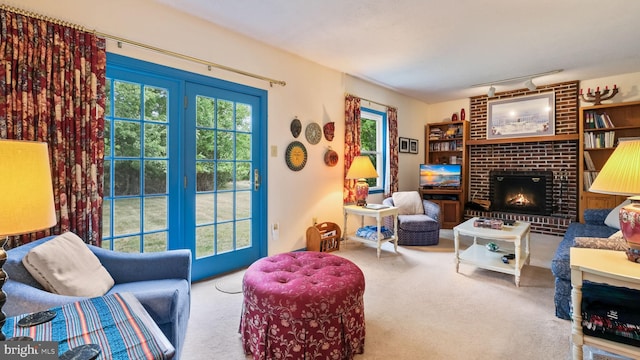 living room featuring brick wall, a fireplace, rail lighting, and carpet flooring