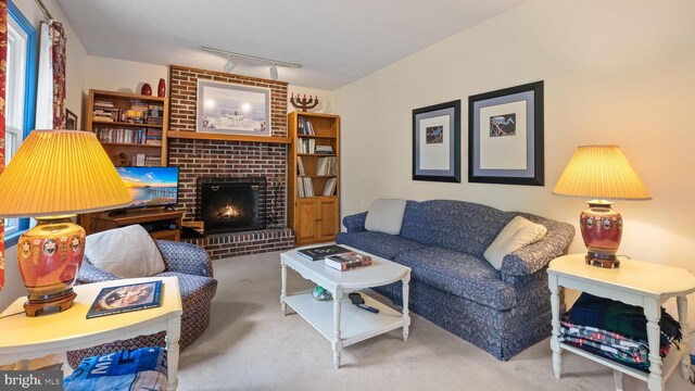 carpeted living room featuring brick wall, a fireplace, and track lighting