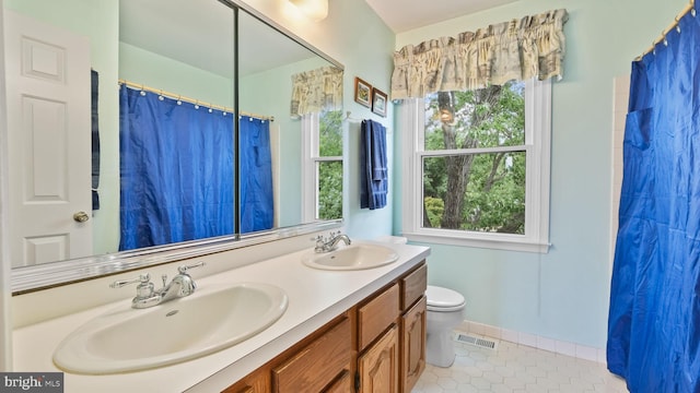 bathroom with toilet, tile patterned floors, and dual bowl vanity