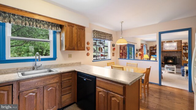 kitchen featuring sink, dishwasher, carpet floors, a brick fireplace, and kitchen peninsula