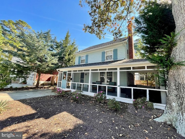 back of property featuring a chimney and a sunroom