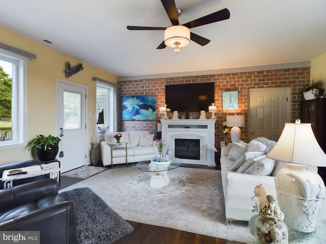 living room featuring a wealth of natural light, brick wall, wood-type flooring, and ceiling fan