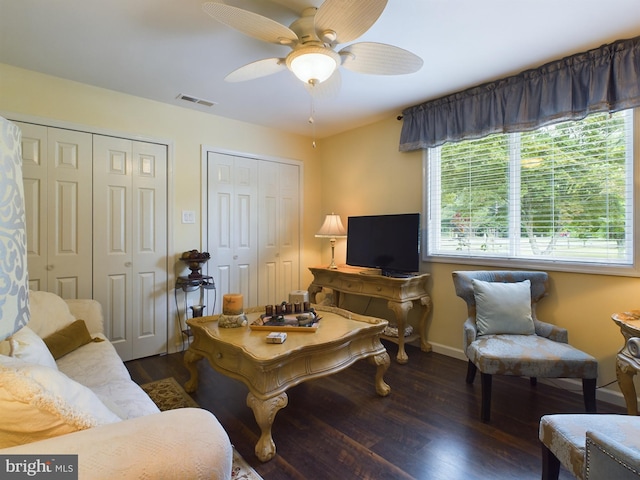 living room featuring dark wood-type flooring and ceiling fan