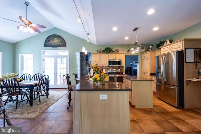 kitchen with appliances with stainless steel finishes, lofted ceiling, light tile patterned floors, a center island, and ceiling fan